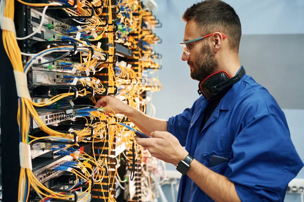 Techniker überprüft verkabelten Serverraum.